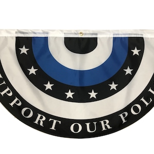 May include: A half-circle flag with a black, white, and blue design. The flag has a thin blue stripe, a white stripe, and a black stripe with white stars. The text "SUPPORT OUR POLICE" is written in a circle around the design.