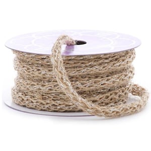 May include: A spool of braided jute ribbon with silver metallic thread woven throughout. The ribbon is a natural tan color, and the spool has a purple label with a decorative pattern. This ribbon is suitable for crafts and gift wrapping.