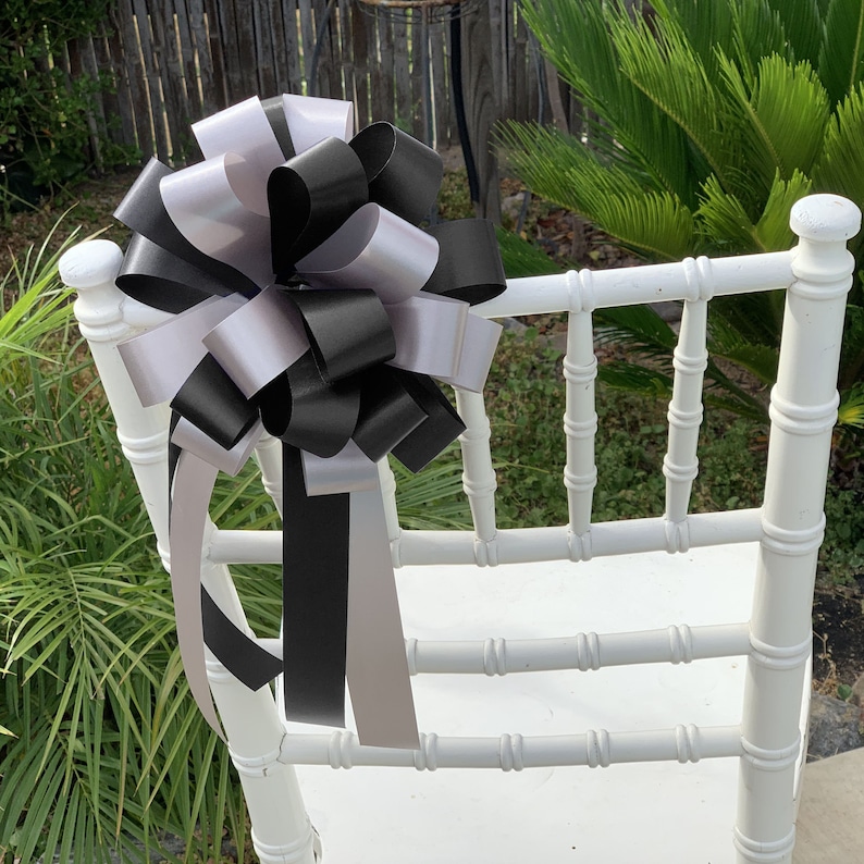 Black and Silver pew bows displayed on a chair.