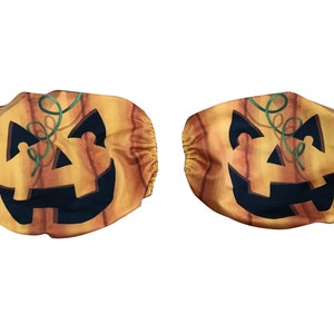 May include: Two orange and brown pumpkin-shaped fabric covers with a jack-o'-lantern face design. The covers have a green stem and a black mouth and eyes.
