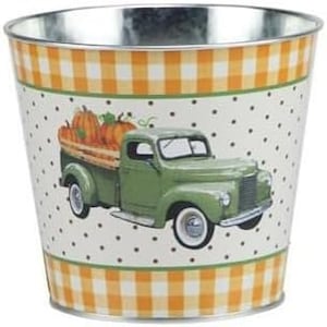 May include: A green vintage truck with a white bed carrying three orange pumpkins on a white background with orange and white gingham and white polka dots. The truck is a metal planter.