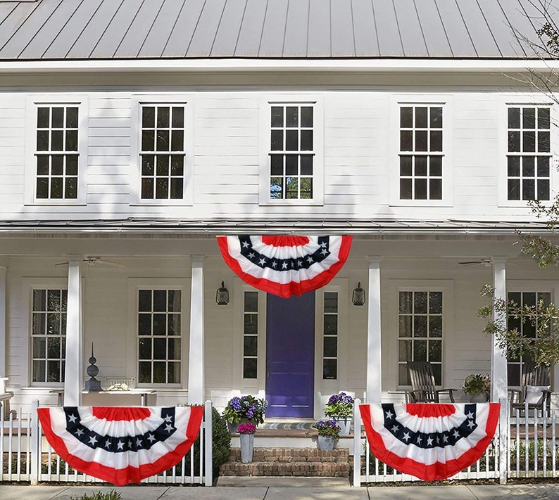 3 Patriotic Bunting Flags displayed on the fence and roof of a beautiful 2 story home.