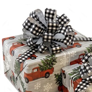 May include: A gift wrapped in red truck and Christmas tree patterned wrapping paper with a black and white buffalo plaid bow on top.