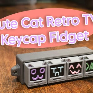 May include: A gray and white keycap fidget toy shaped like a row of retro televisions with cat faces on the screens. The screens have different expressions, including a winking face, a sad face, a happy face, and a face with a sideways smile.