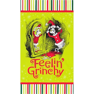 May include: A green Christmas-themed towel with a cartoon Grinch character in a red and white Santa suit looking in a mirror. The text "Feelin' Grinchy" is printed on the towel.
