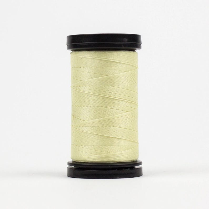 May include: A spool of pale yellow thread wound on a black plastic bobbin.