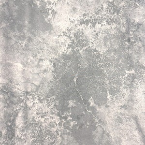 May include: A close-up of a fabric with a mottled, marbled appearance. The color palette is primarily gray and white, with a textured, weathered look. The fabric has a scale in inches at the bottom.
