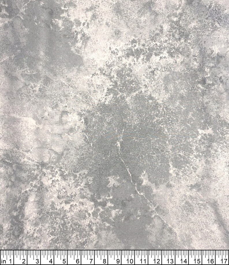 May include: A close-up of a fabric with a mottled, marbled appearance. The color palette is primarily gray and white, with a textured, weathered look. The fabric has a scale in inches at the bottom.