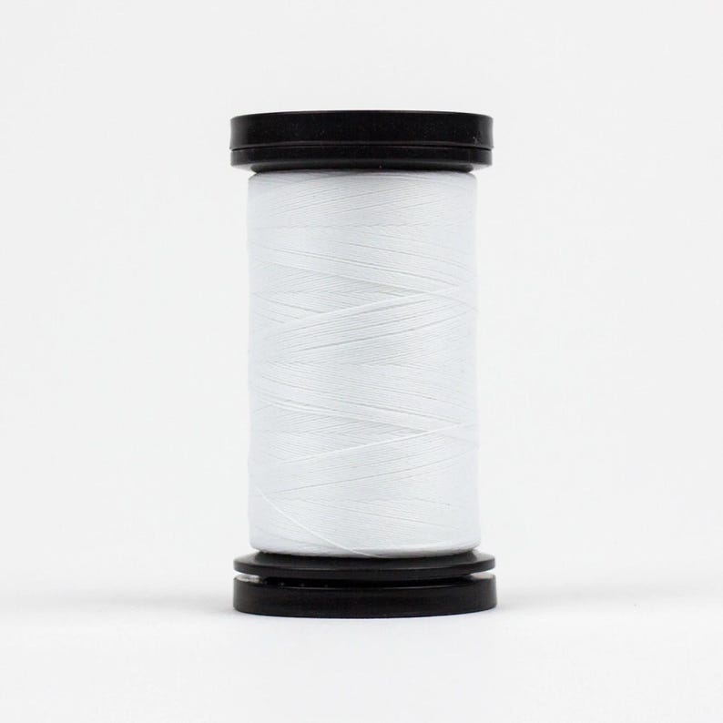 May include: A spool of white thread with a black plastic top and bottom.
