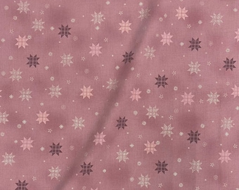 May include: Dusty rose fabric featuring a repeating pattern of stars and snowflake shapes in shades of pink and silver. The fabric has a slightly textured appearance, with subtle variations in colour and tone. The design is evenly distributed across the surface.
