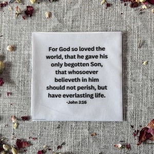 May include: A square white fabric patch featuring black printed text that reads: For God so loved the world, that he gave his only begotten Son, that whosoever believeth in him should not perish, but have everlasting life. -John 3:16.