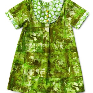 May include: A green and white patterned dress with short sleeves and a white collar with polka dots. The collar has yellow buttons.