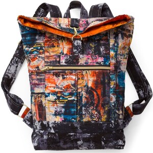 May include: A black canvas backpack with a large flap and a zippered pocket. The backpack has a colorful abstract print with orange, blue, and yellow accents.