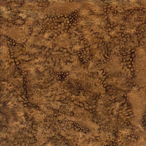 May include: A close-up view of a brown fabric with a mottled pattern. The fabric has a mix of light and dark brown tones, with small, irregular shapes scattered across the surface. The overall texture appears slightly rough.