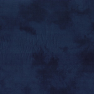 Puede incluir: Primer plano de una tela azul oscuro con un patrón tie-dye. El material tiene una superficie texturizada con áreas más oscuras, creando un efecto nublado. Se ven pliegues y variaciones de color.