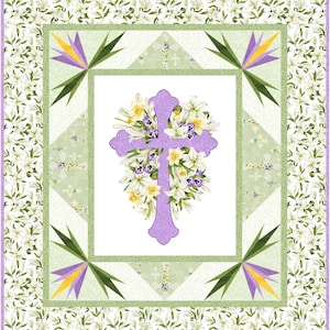 May include: A quilted fabric featuring a large, lavender cross adorned with white lilies, yellow daffodils, and purple pansies. The cross is centered within a white square, framed by green and white patterned borders with floral and geometric designs. The outer border is white with a lily pattern.