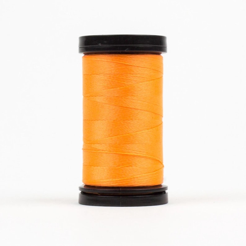 May include: A spool of bright orange thread with black plastic caps on either end.