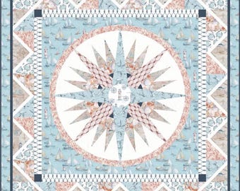 Puede incluir: Una colcha de estilo náutico azul y blanco con un diseño de brújula en el centro. La brújula está rodeada por un borde de conchas marinas, anclas y veleros. La colcha está hecha de tela de patchwork y tiene una textura acolchada.
