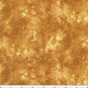 May include: A seamless fabric with a watercolor-like pattern in shades of gold and brown. The design features irregular, organic shapes that create a mottled effect. The fabric has a textured appearance, suggesting a woven material.