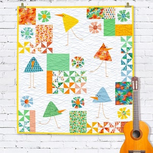 Puede incluir: Una colcha colorida con un diseño de patchwork que presenta pájaros, flores y formas geométricas. La colcha está hecha con una variedad de telas en tonos de azul, verde, amarillo, naranja y rojo.