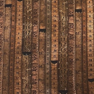 May include: A close-up of multiple vintage wooden rulers with faded brown and black markings. The rulers are lined up side-by-side, creating a pattern of numbers and lines.