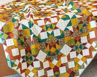 May include: A quilt with a patchwork design featuring a variety of autumnal colors, including red, orange, yellow, green, and brown. The quilt is made up of squares and triangles, and the fabric has a floral pattern.
