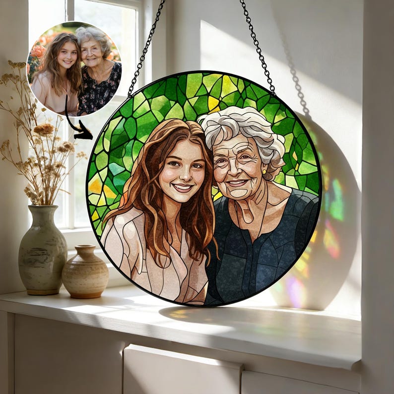 May include: A round stained glass art piece featuring a portrait of two smiling women. The background is a mosaic of green glass. The artwork is suspended by a black chain. A smaller photo of the women is in the upper left corner.