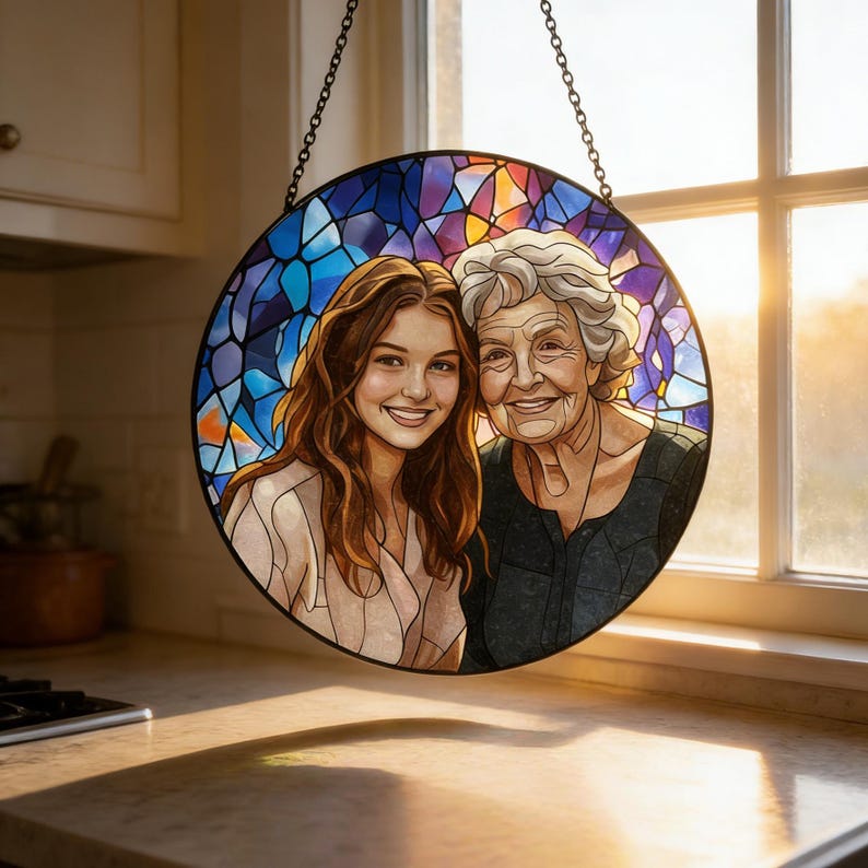 May include: A round stained glass window featuring a portrait of two smiling women. The background is a mosaic of blue, purple, and orange glass. The window is framed in black and suspended by a chain. The women are depicted with realistic features and warm expressions.