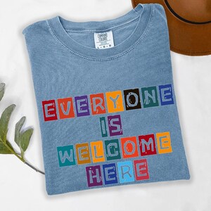 Camiseta Todos São Bem-vindos Aqui, Camiseta com Mensagem Positiva, Camiseta Inclusiva, Camiseta Gráfica de Boas-vindas, Camiseta com Letras Coloridas, Ajuste Unissex