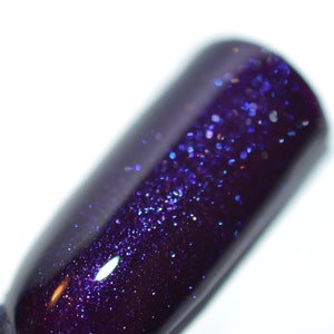 May include: A close-up of a dark purple nail polish with a fine shimmer of iridescent glitter.