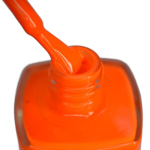 May include: A close-up of a bottle of bright orange nail polish with the cap off and the brush dipped in the polish.