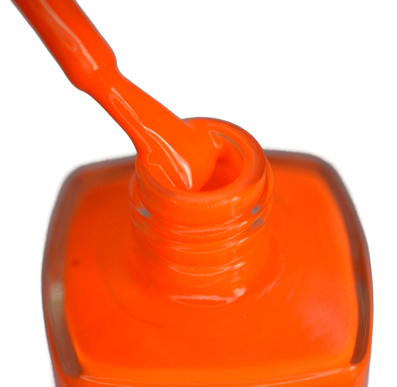 May include: A close-up of a bottle of bright orange nail polish with the cap off and the brush dipped in the polish.