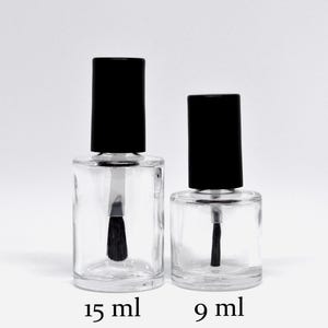 May include: Two clear glass bottles with black caps and brushes. The bottle on the left is labelled 15 ml and the bottle on the right is labelled 9 ml.