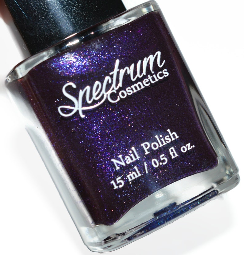 May include: A bottle of Spectrum Cosmetics nail polish in a deep purple colour with silver glitter. The bottle is labelled "Nail Polish" and "15 ml / 0.5 fl oz."