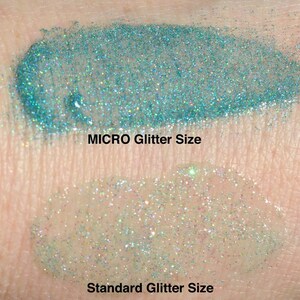 May include: Close-up of two swatches of glitter on skin. The top swatch is labeled "MICRO Glitter Size" and shows fine glitter. The bottom swatch is labeled "Standard Glitter Size" and shows larger glitter.