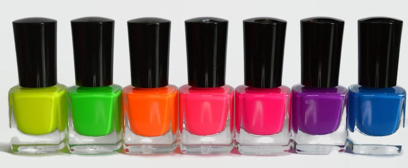 May include: Seven bottles of neon nail polish in different colors, including yellow, green, orange, pink, magenta, purple, and blue.