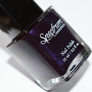May include: A bottle of Spectrum Cosmetics nail polish in a deep purple colour with a shimmer finish. The bottle is labelled "Nail Polish" and "15 ml / 0.5 fl oz".
