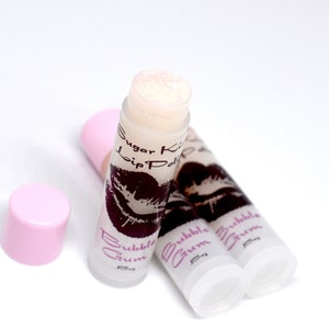 May include: Three pink and white lip balm tubes with a clear lid. The tubes are labelled "Sugar Kiss Lip Polish" and "Bubble Gum".