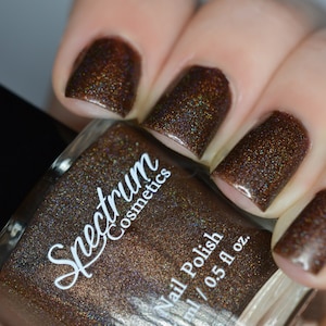 May include: A bottle of Spectrum Cosmetics nail polish in a brown color with a shimmer finish. The bottle is labeled "Spectrum Cosmetics" and "Nail Polish".