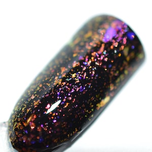 May include: Black nail polish with iridescent gold and purple glitter flakes.