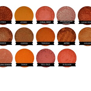May include: A collection of 15 round eyeshadows in various shades of orange, red, and brown. The eyeshadows are arranged in three rows of five. Each eyeshadow has a name printed below it.