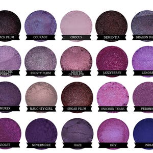 May include: A collection of 20 small round jars of purple, blue, and pink eyeshadow. Each jar has a black label with the name of the eyeshadow color printed in white.