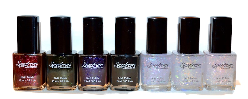 May include: Eight bottles of Spectrum Cosmetics nail polish in various colours, including red, green, purple, black, and silver. Each bottle is labelled "Nail Polish" and contains 15 ml / 0.5 fl oz.