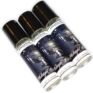 May include: Three glass roll-on bottles of Midnight Rain perfume by Spectrum Cosmetics. Each bottle is 0.35 fl oz and features a black and white illustration of a cityscape at night.