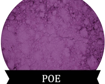 May include: A close-up of a purple powder pigment. The powder is in a round container and has a textured surface. The word "POE" is printed in white on a black ribbon.