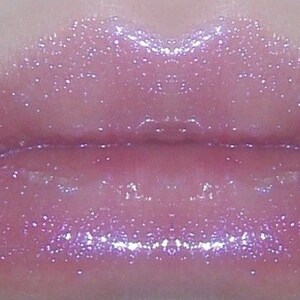 May include: Close-up of a pair of lips wearing a light pink lip gloss with iridescent glitter.