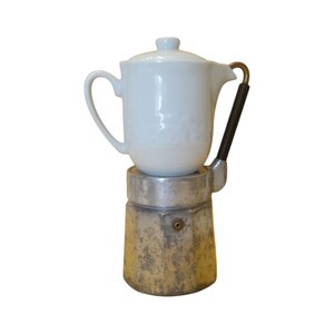 May include: A vintage stovetop espresso maker with a white ceramic top and a weathered, metallic base. The handle is black with a brass accent. This classic coffee maker is a kitchen essential.