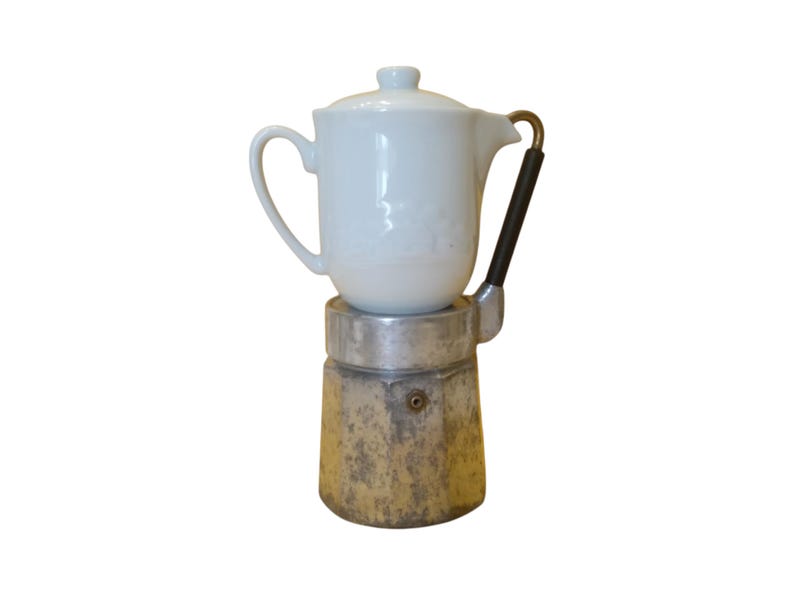 May include: A vintage stovetop espresso maker with a white ceramic top and a weathered, metallic base. The handle is black with a brass accent. This classic coffee maker is a kitchen essential.