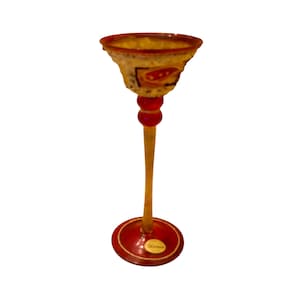 Puede incluir: Un vaso decorativo alto con una parte superior acampanada y un tallo delgado. El vaso presenta una base y detalles en rojo, con un tallo y cuenco amarillos. El cuenco tiene un diseño estampado con detalles rojos y blancos. El vaso es probablemente un artículo decorativo.