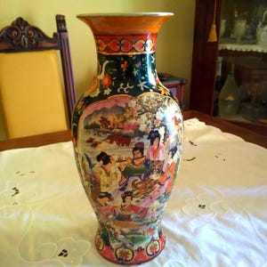Pu&ograve; includere: Un vaso decorativo in ceramica con bocca larga e base svasata. Il vaso presenta una scena dipinta dettagliata con figure, animali e paesaggi dai colori vivaci. Il bordo &egrave; arancione e il corpo &egrave; verde scuro.